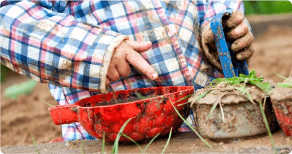 A child playing with plants and mud